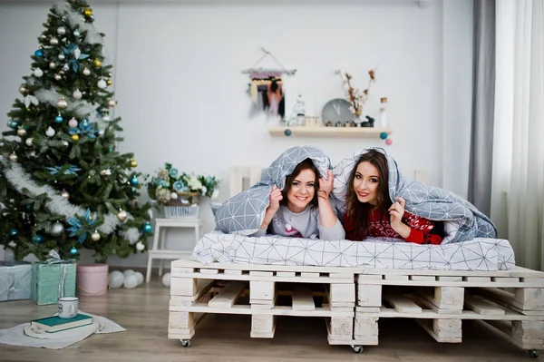 Dwie dziewczyny noszą na swetry zimowe zabawy na łóżku, roo — Zdjęcie stockowe