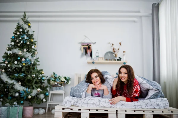 Dvě přítelkyně nosí na zimní svetry baví na posteli v roo — Stock fotografie
