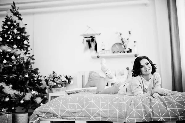 Dívka nosí na zimní svetr posteli na pokoji s vánoční stromeček. — Stock fotografie