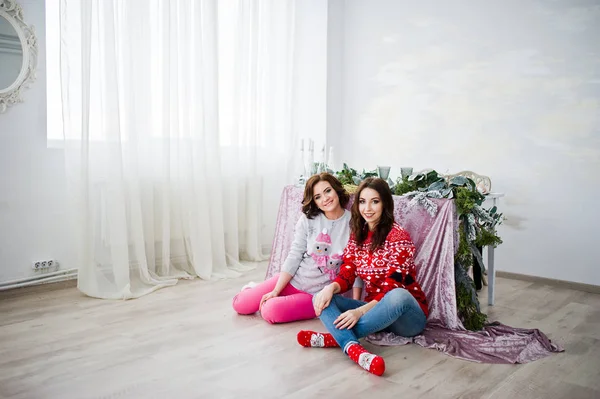 Two girlfriends wear on winter sweaters sitting against table at — Stock Photo, Image