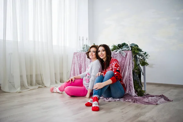 Two girlfriends wear on winter sweaters sitting against table at — Stock Photo, Image