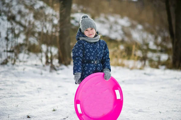 Cute little girl with saucer sleds outdoors on winter day. — Stock Photo, Image