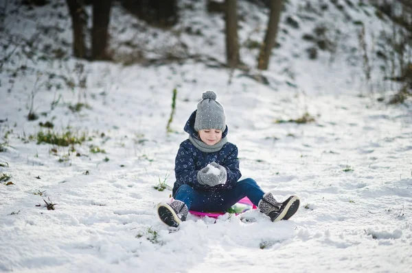 Söt liten flicka med tefat slädar utomhus vinterdag. — Stockfoto