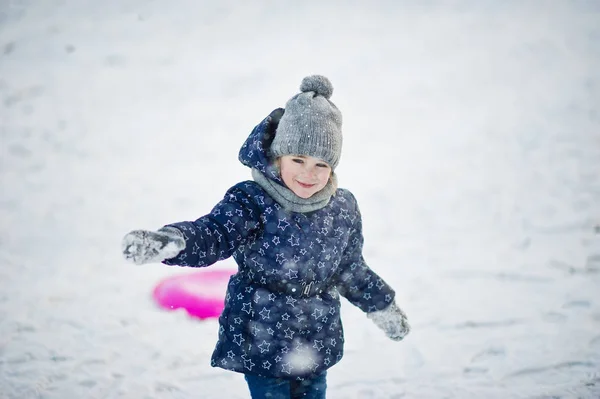Söt liten flicka med tefat slädar utomhus vinterdag. — Stockfoto