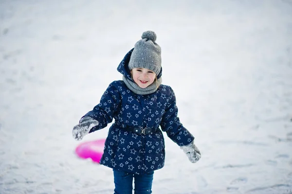 Söt liten flicka med tefat slädar utomhus vinterdag. — Stockfoto