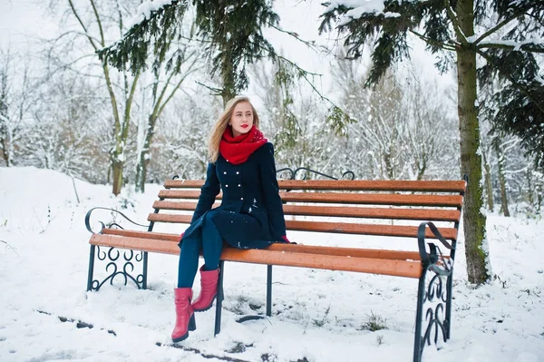 Menina loira em cachecol vermelho e casaco sentado no banco no dia de inverno — Fotografia de Stock