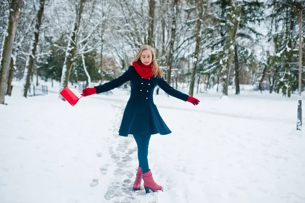 Menina loira em cachecol vermelho e casaco andando no parque no dia de inverno . — Fotografia de Stock