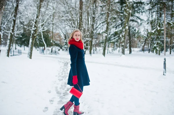 Blond meisje in de rode sjaal en jas lopen in het park op de winterdag. — Stockfoto