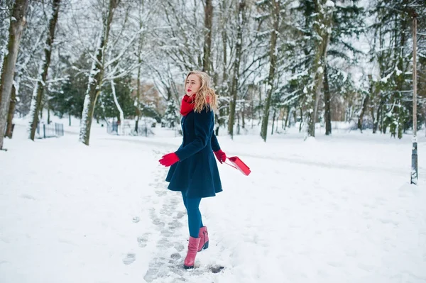 Menina loira em cachecol vermelho e casaco andando no parque no dia de inverno . — Fotografia de Stock