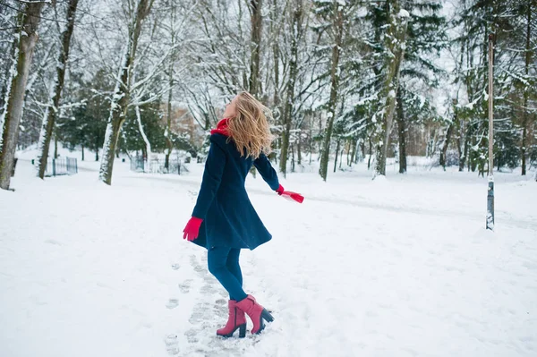 Blond meisje in de rode sjaal en jas lopen in het park op de winterdag. — Stockfoto