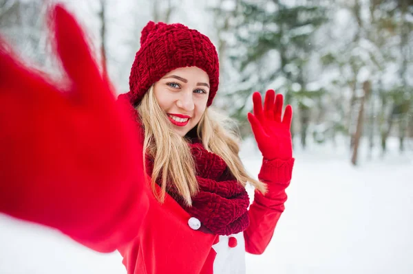 Ragazza bionda in sciarpa rossa, cappello e maglione di Babbo Natale in posa al parco — Foto Stock