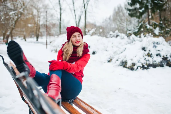 Блондинка в красном шарфе, шляпе и свитере Санты позирует в парке — стоковое фото