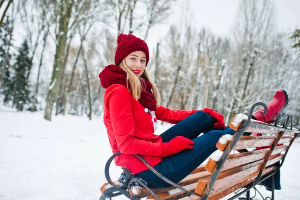 Блондинка в красном шарфе, шляпе и свитере Санты позирует в парке — стоковое фото