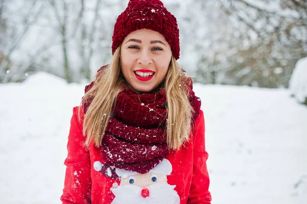 Ragazza bionda in sciarpa rossa, cappello e maglione di Babbo Natale in posa al parco — Foto Stock