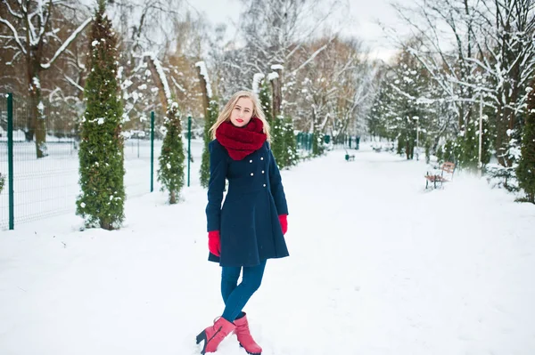 Blond meisje in de rode sjaal en jas lopen in het park op de winterdag. — Stockfoto