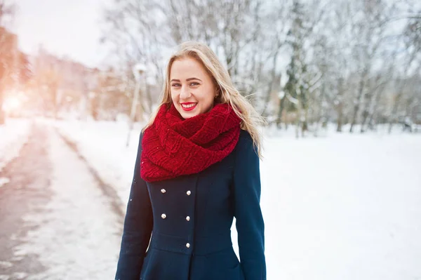 Ragazza bionda in sciarpa rossa e cappotto a piedi al parco nella giornata invernale . — Foto Stock