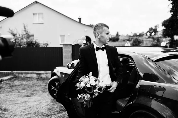 Portrait of a handsome groom walking out of the car with a weddi — Stock Photo, Image