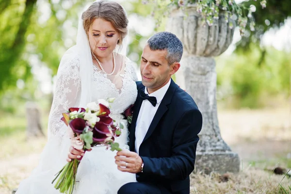 Aantrekkelijke bruid zittend op schoot van van de bruidegom buiten op de weddi — Stockfoto