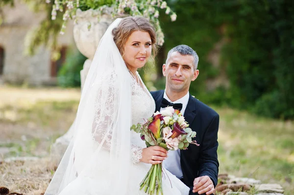 Aantrekkelijke bruid zittend op schoot van van de bruidegom buiten op de weddi — Stockfoto