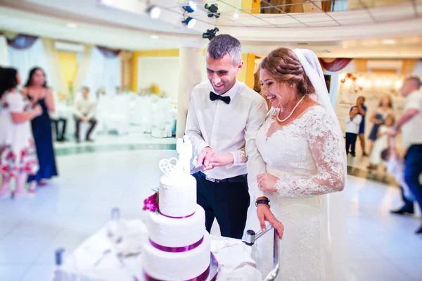 Casamento casal cortando seu grande bolo branco dentro do restauran — Fotografia de Stock