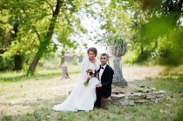 Aantrekkelijke bruid zittend op schoot van van de bruidegom buiten op de weddi — Stockfoto