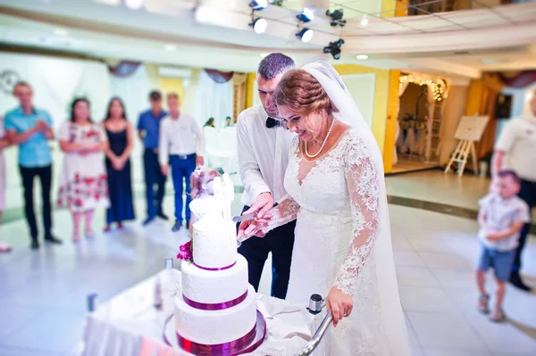 Pareja de boda cortando su gran pastel blanco dentro del restaurante —  Fotos de Stock