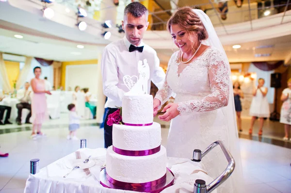 Wedding couple cutting their big white cake inside the restauran — Stock Photo, Image