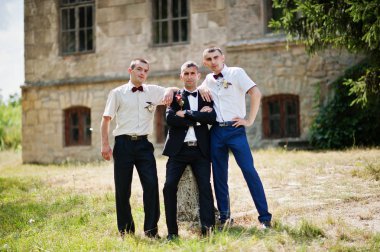 T yanındaki bir güneşli düğün gününde iki sağdıç ile poz damat