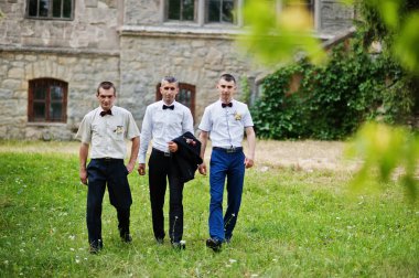 T yanındaki bir güneşli düğün gününde iki sağdıç ile poz damat