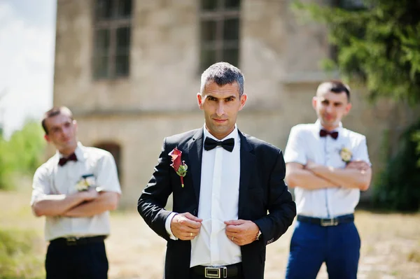 Groom posing with two groomsmen on a sunny wedding day next to t — Stock Photo, Image