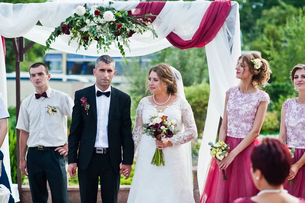 Couple de mariage faisant vœux en plein air sous l'arche florale en fron — Photo