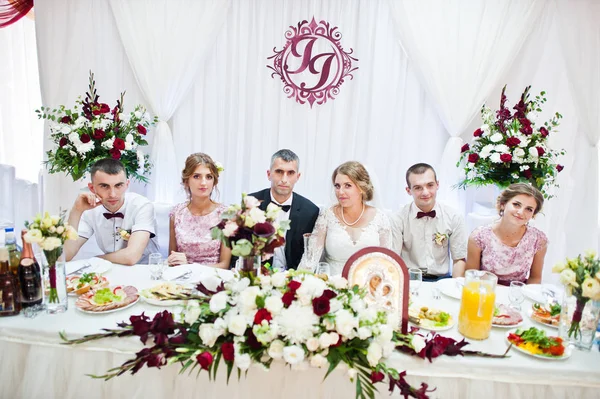 Joven pareja de boda sentada en la mesa festiva junto con bri —  Fotos de Stock