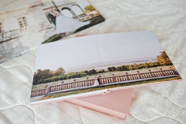 Seiten mit Hochzeitsfotos eines Fotobuchs oder Fotoalbums auf dem Bett. — Stockfoto