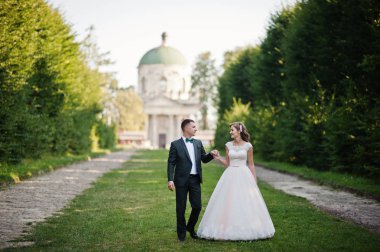 Güzel düğün çift uzanan yeşil sokak yürüyüş 