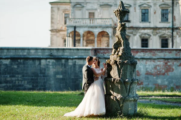 Bonito casal recém-casado beijando ao lado de uma fonte velha no — Fotografia de Stock