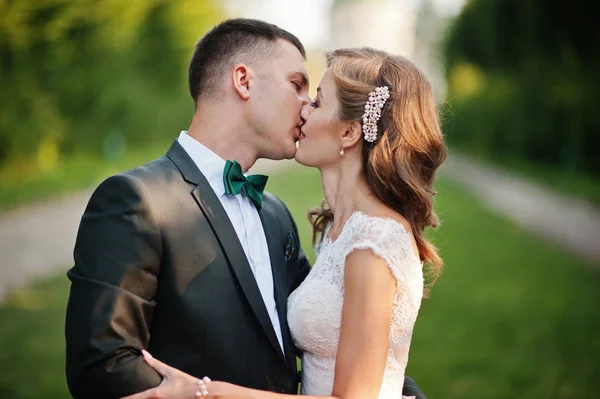 Preciosa pareja de boda besándose en el callejón verde que conduce a — Foto de Stock