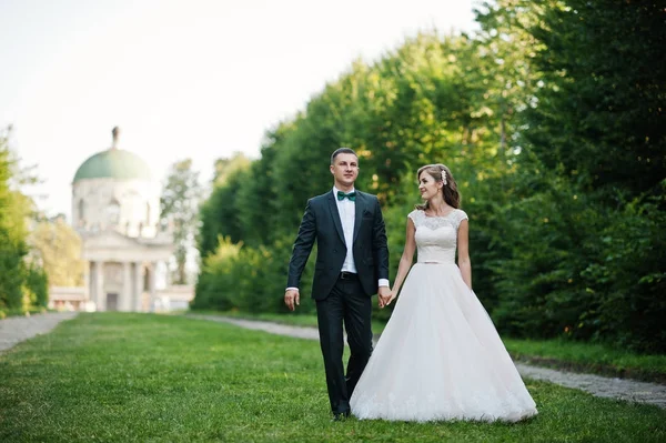 Härliga bröllop par promenader längs den gröna gränd som leder — Stockfoto