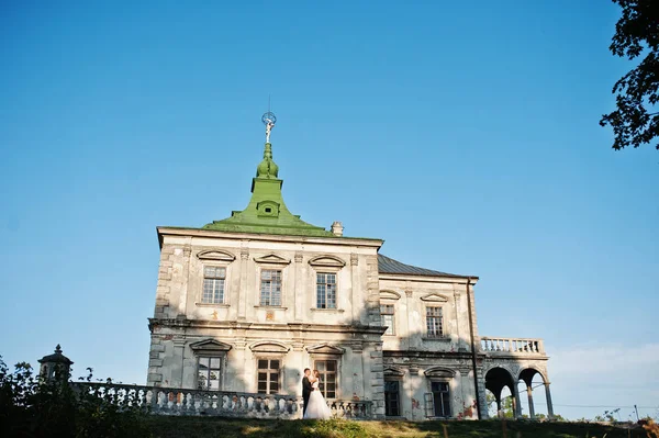 Fabelhaftes Hochzeitspaar posiert vor einem alten mittelalterlichen Schloss — Stockfoto