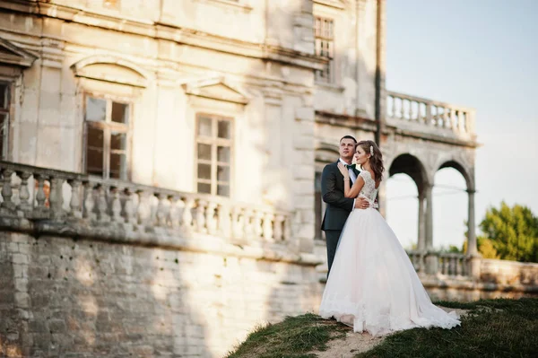 Fabuloso casal de casamentos posando na frente de um velho castelo medieval — Fotografia de Stock