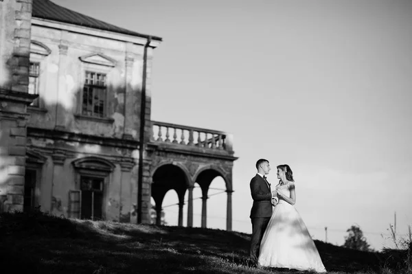 Fabuloso casal de casamentos posando na frente de um velho castelo medieval — Fotografia de Stock