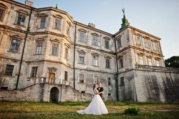 Fabuloso casal de casamentos posando na frente de um velho castelo medieval — Fotografia de Stock