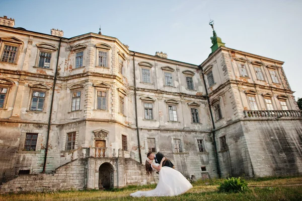 Fabuloso casal de casamentos posando na frente de um velho castelo medieval — Fotografia de Stock