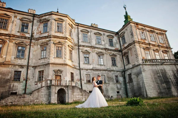 Fabuloso casal de casamentos posando na frente de um velho castelo medieval — Fotografia de Stock