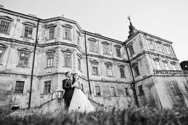 Fabuloso casal de casamentos posando na frente de um velho castelo medieval — Fotografia de Stock