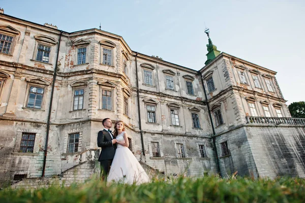 Fabuloso casal de casamentos posando na frente de um velho castelo medieval — Fotografia de Stock