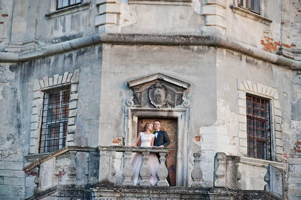 Mooie bruidspaar poseren naast de belangrijkste kasteel deuren. — Stockfoto