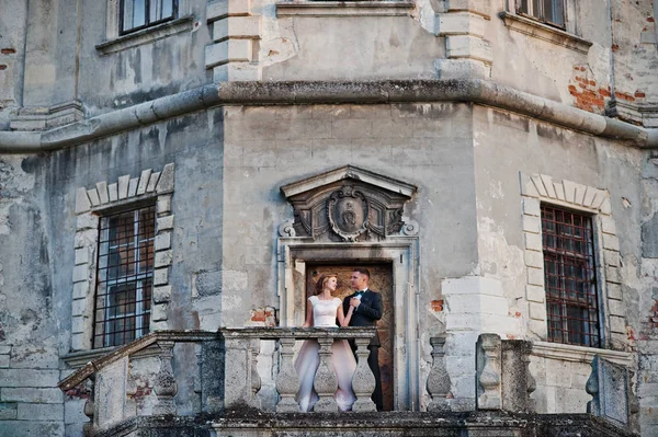 Beau couple de mariage posant à côté des portes principales du château . — Photo