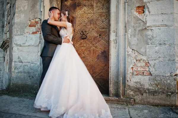 Beau couple de mariage posant à côté des portes principales du château . — Photo