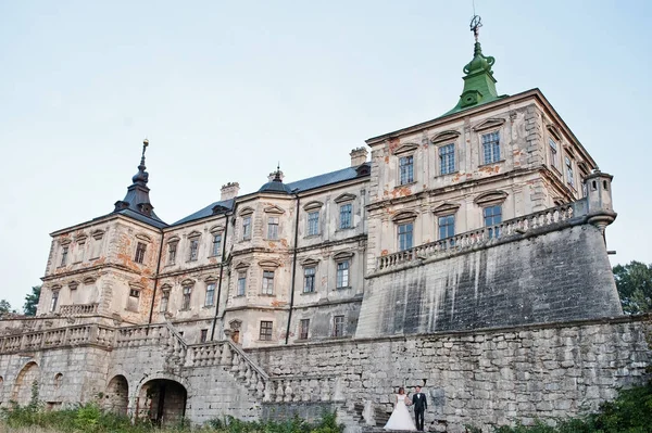 Fabelhaftes Hochzeitspaar posiert vor einem alten mittelalterlichen Schloss — Stockfoto