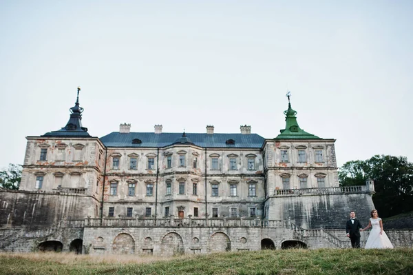 Fabuloso casal de casamentos posando na frente de um velho castelo medieval — Fotografia de Stock